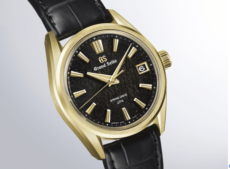 GRAND SEIKOBosque de hielo al amanecer SLGB006 CARÁTULA Watches World Gold Grand Seiko wristwatch with black speckled dial date window at 3 oclock and black leather strap