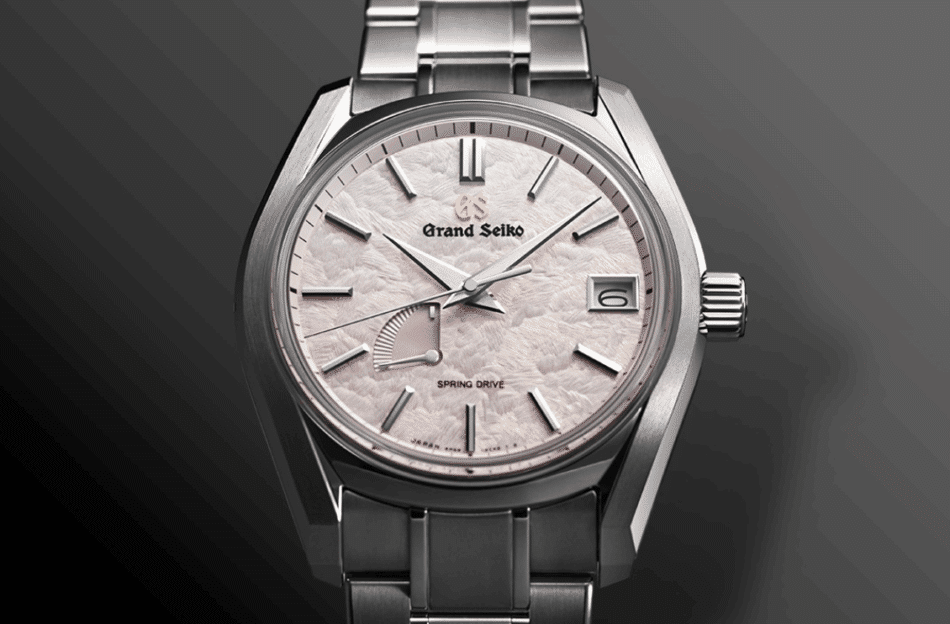 Grand Seiko 62GS Shunbuncaratula completa Watches World Close up of a stainless steel Grand Seiko watch with a pale pink textured dial date window at 3 and metal bracelet