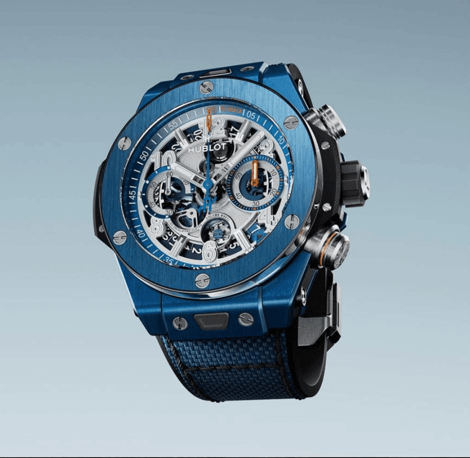 HUBLOT Reloaded BLUE CERÁMIC Watches World Blue skeleton wristwatch with exposed gears and a blue fabric strap shown in a diagonal side view on a gradient background