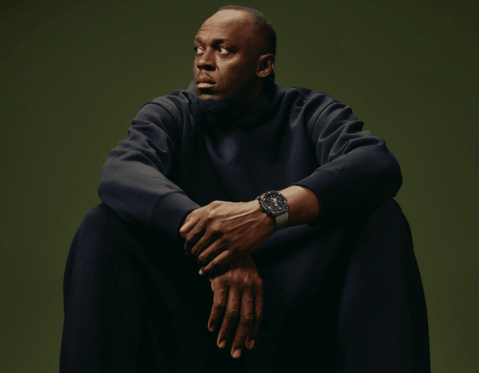 HUBLOTBig Bang Reloaded Usain BoltUSAIN BOLT Watches World Man seated in a dark hoodie with a large watch looking to the left against a muted green backdrop