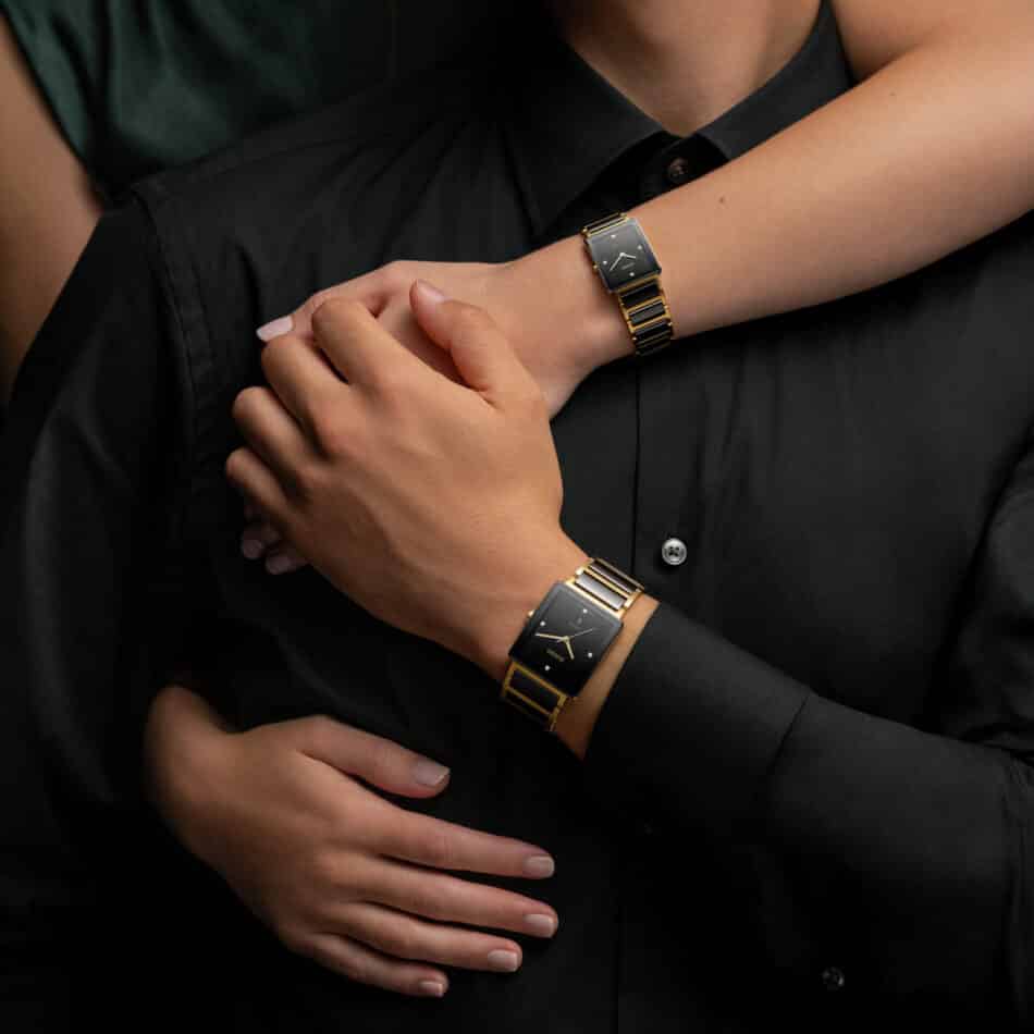 IntegralR20252702R20256712wrist1 Watches World Dos personas con camisas negras llevan relojes cuadrados a juego de color dorado y negro con un brazo sobre el otro