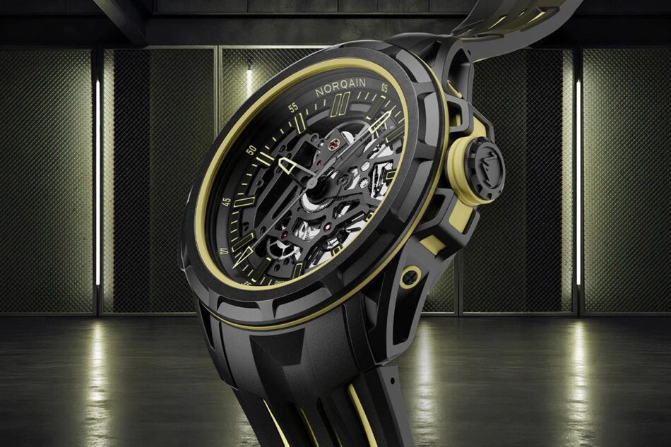Norqain Wild ONE Skeleton XLite 5 Watches World Skeleton wristwatch with black case and gold accents exposing inner gears against a dark industrial backdrop