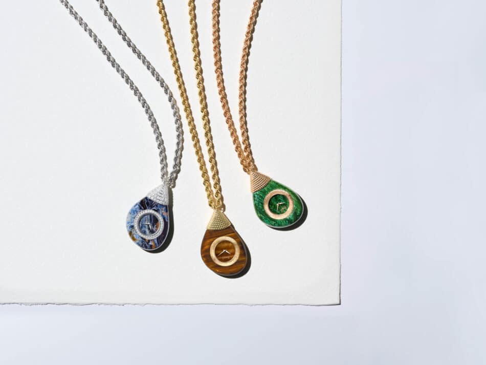 Piaget Swinging Pebbles relojes colgantes que celebran el movimiento Watches World Tres colgantes de piedras preciosas en forma de lágrima con cadenas de oro que cuelgan sobre un fondo con un degradado de negro a marrón naranja verde azul