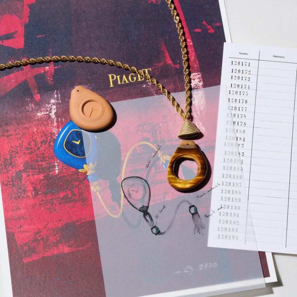 Piaget Swinging Pebbles Watches World Collar de cadena de oro con dos colgantes de color tostado sobre un folleto de Piaget junto a una hoja con inscripciones numeradas