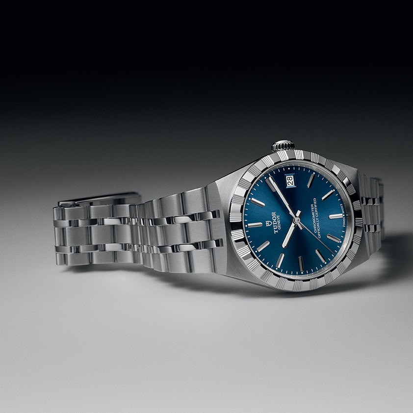 TUDOR Royal el reloj deportivo elegante se reinventa Watches World Reloj de pulsera de acero inoxidable con carátula azul ventana de fecha a las 3 en punto y brazalete de metal cepillado sobre un fondo neutro