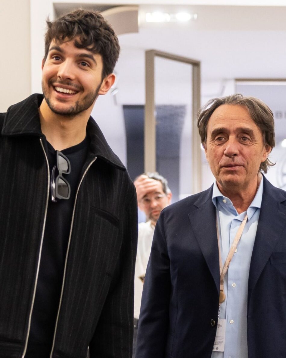 Watches and Wonders Geneva 2026 10 Watches World Watches and Wonders Geneva 2026Two men smile for a photo at an indoor event a younger man on the left in a black zip jacket with sunglasses hanging from his chest and a older man on the right in a blue blazer and light shirt
