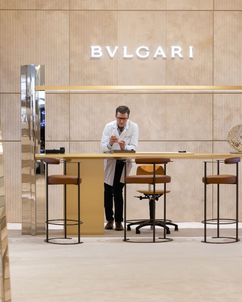 Watches and Wonders Geneva 2026 14 Watches World Watches and Wonders Geneva 2026 A man in a white coat stands at a long wooden counter inside a BVLGARI store inspecting a small object in his hands