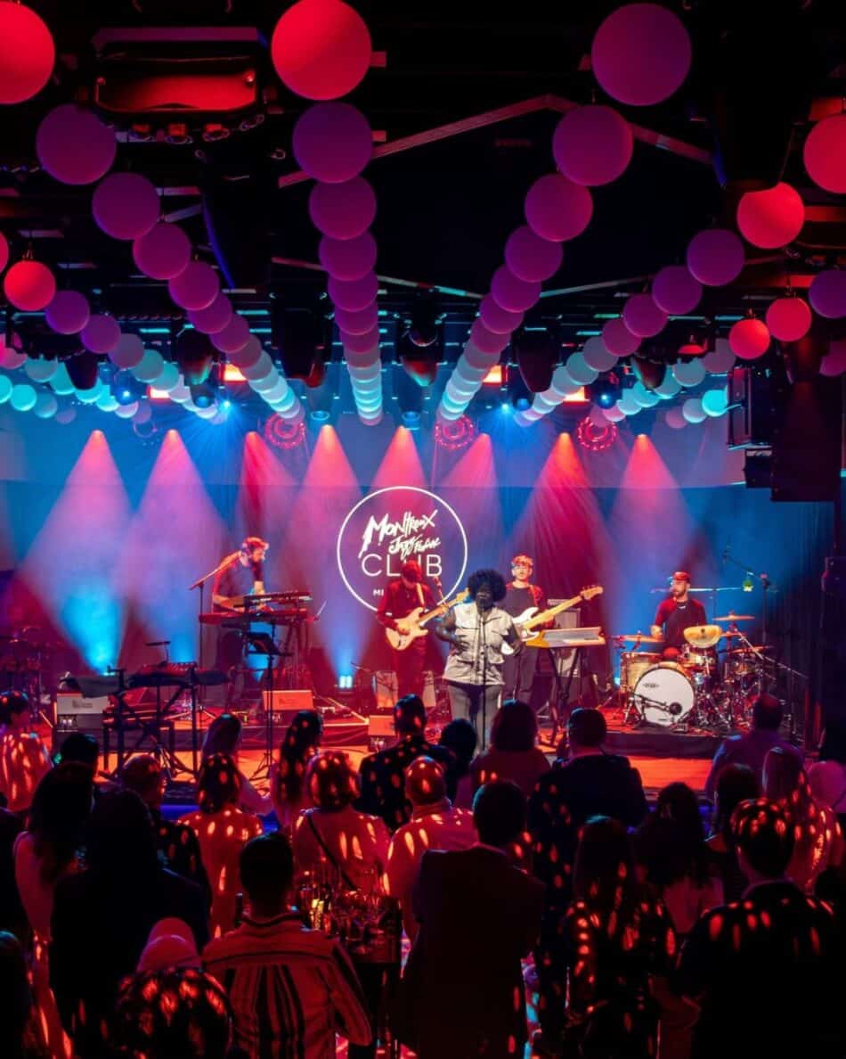 Watches and Wonders Geneva 2026 18 Watches World Watches and Wonders Geneva 2026 Live band performing on stage under pink and blue lights with balloons hanging from the ceiling and a cheering audience in front