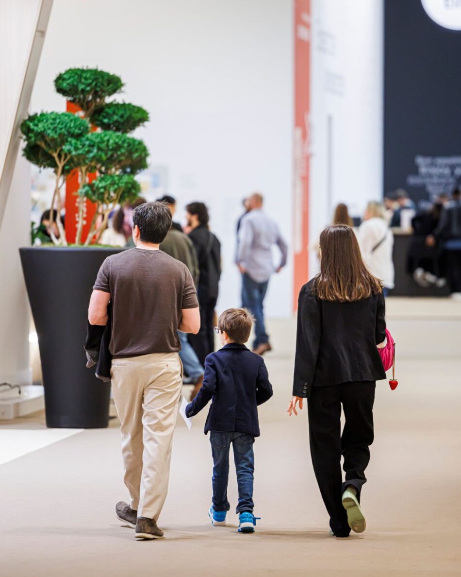 Watches and Wonders Geneva 2026 4 Watches World Watches and Wonders Geneva 2026 Family of three walking away in a bright exhibition hall with a large potted tree