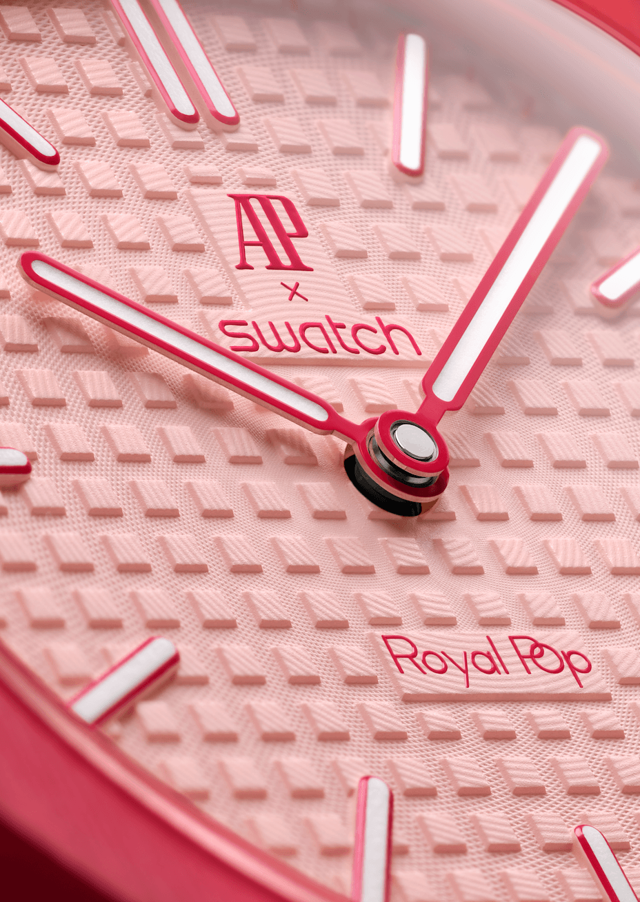 Audemars Piguet × SwatchOTTO ROSSO DETALLE CARÁTULA Watches World Close up of a pink Swatch watch dial with a textured pattern pink hands and AP x Swatch branding including Royal Pop
