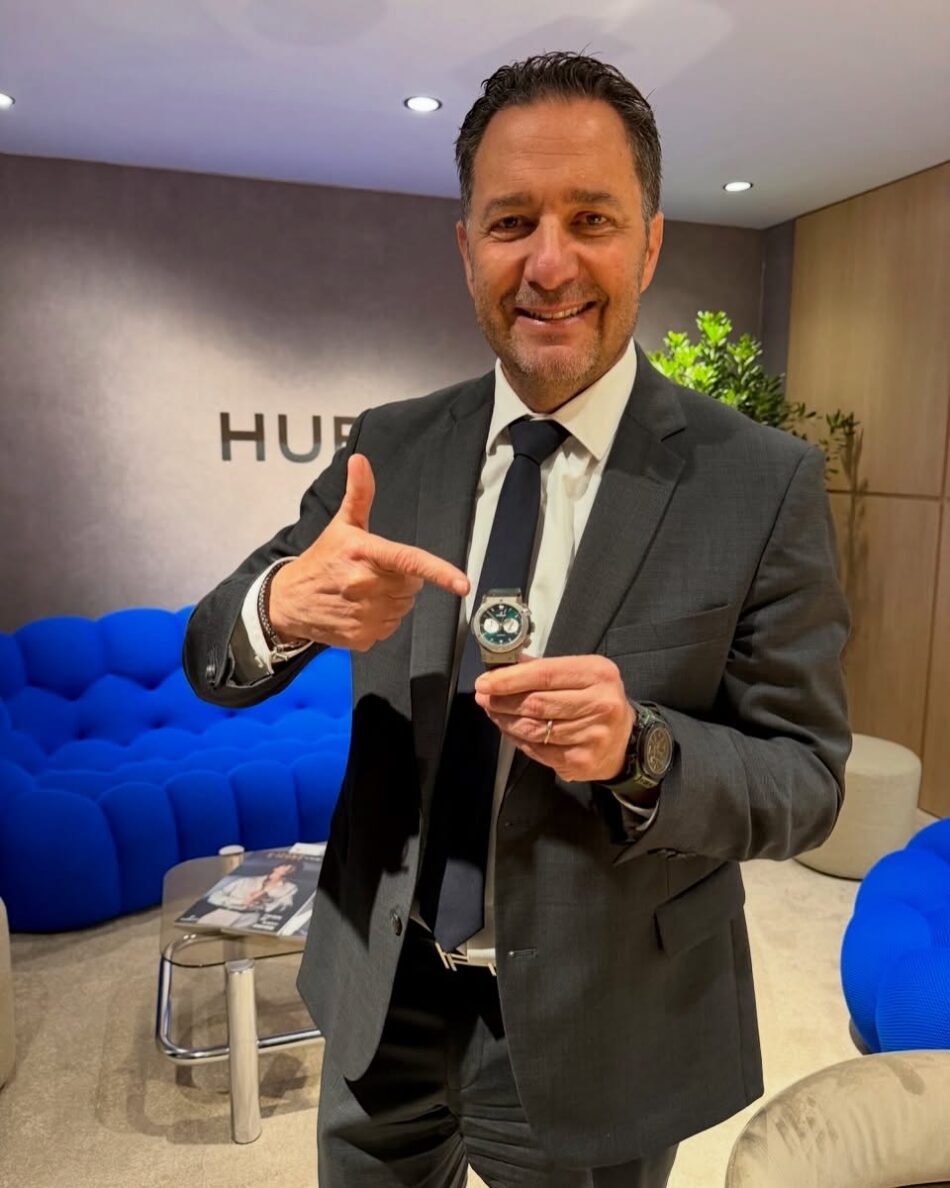 Hublot Classic Fusion Chronograph SNM Titanium Julien Tornare Watches World Julien Tornare Hublot Classic Fusion Chronograph SNM Titanium Julien TornareHublot Classic Fusion Chronograph SNM Titanium Julien Tornare Man in a suit smiling and pointing at a wristwatch he is holding up in a modern lounge area