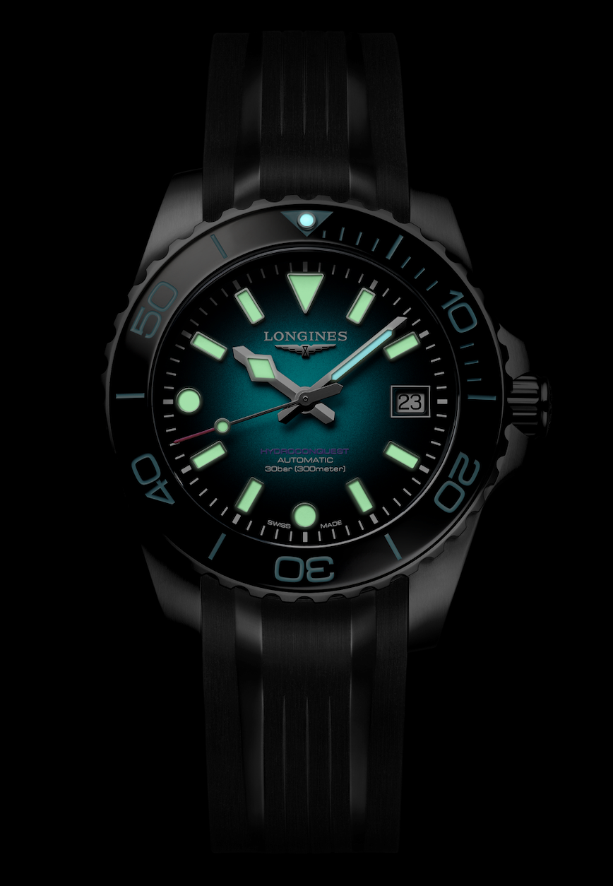 Longines HydroConquest Commonwealth Games 2026OSCURO Watches World Reloj de buceo Longines HydroConquest con índices y agujas de color verde azulado luminiscentes ventana de fecha a las 3 en punto bisel negro y correa negra sobre un fondo oscuro