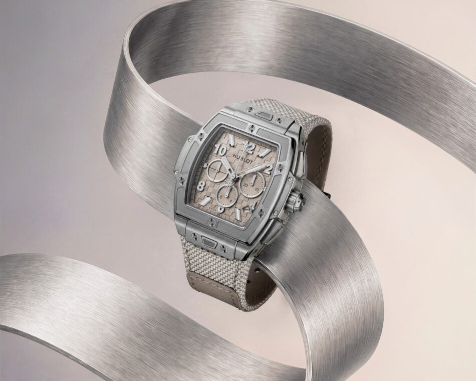 Spirit of Big Bang Essential Taupe 14 Watches World Primer plano de un reloj cronógrafo de lujo plateado con una esfera beige con textura envuelto en una cinta de metal cepillado