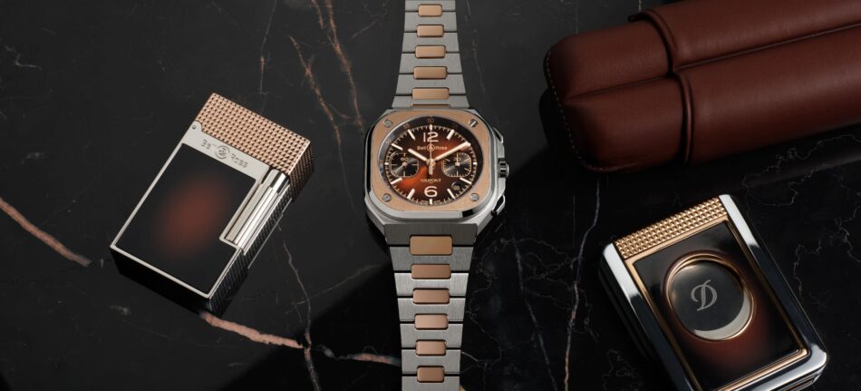 Bell Ross BR05 Chrono ST Dupont 5 Watches World Luxurious collection of watches and accessories on a dark marble surface centered by a two tone Bell Ross watch with a metal bracelet and brown dial