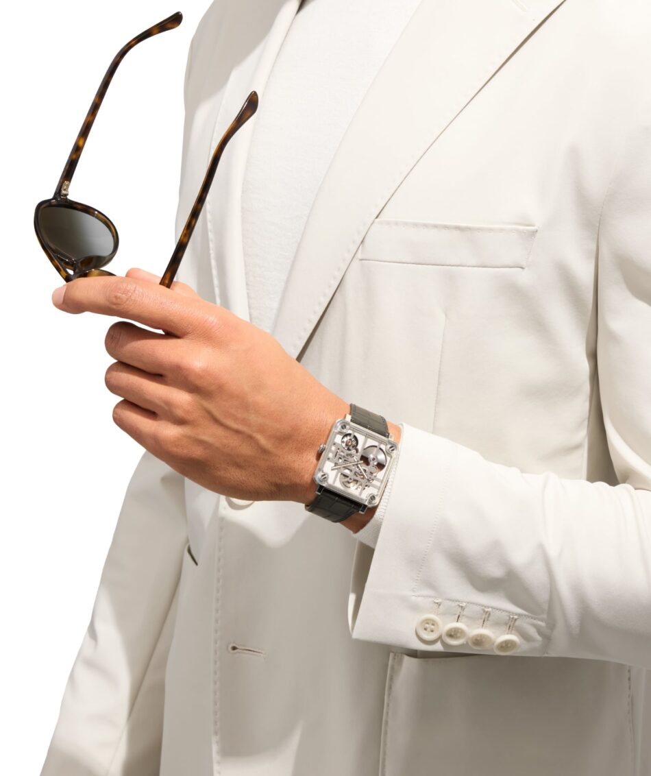 Bell Ross BRX3 MicroRotor 3 Watches World Bell Ross BR X3 Micro Rotor Person in a cream suit holds tortoiseshell sunglasses in their left hand wearing a skeleton style wristwatch visible on the other arm