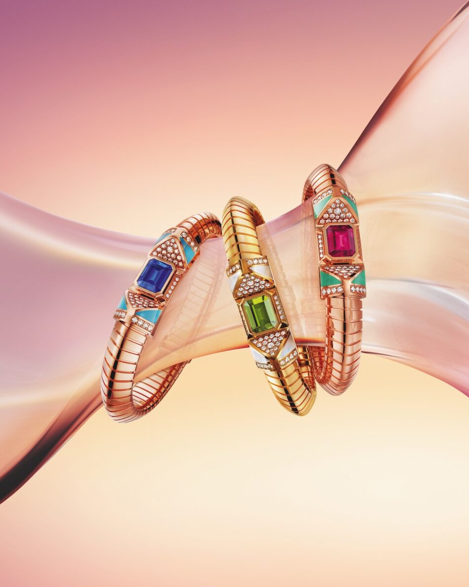 COMPBRACCIALICMYK copy Watches World Tres pulseras de eslabones en tono dorado adornadas con grandes gemas de colores y diamantes sobre un fondo de satén rosa
