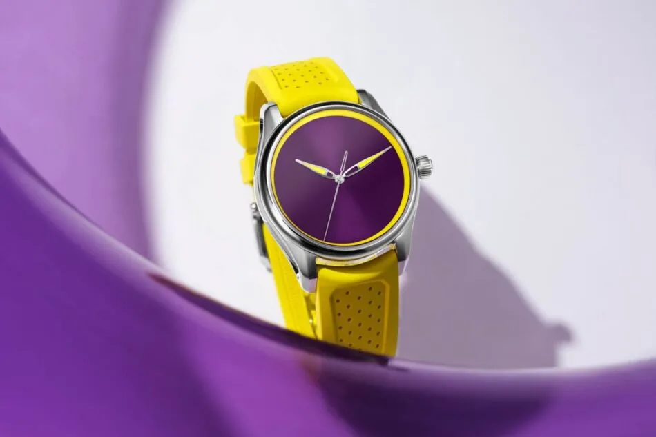Reloj con correa de silicona amarilla y carátula morada sobre una superficie morada brillante.