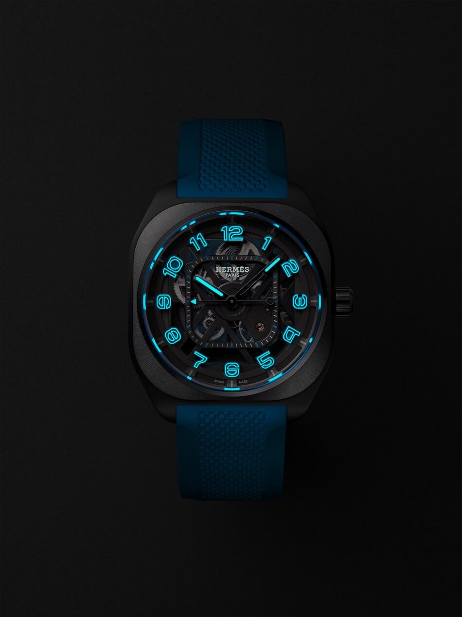 HermesH08SquelettecopyrightJoelVonAllmen copy Watches World Hermes H08 Squelette con iluminación azul caja negra y correa azul sobre un fondo oscuro en el que se aprecian los números y los engranajes luminosos