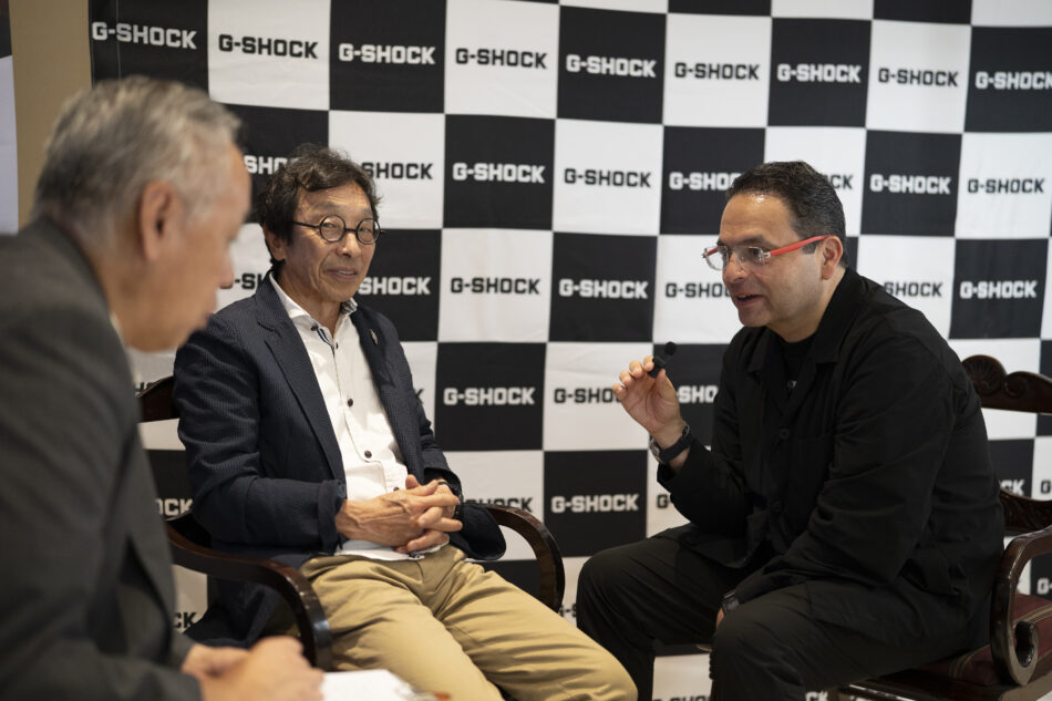 IBE GSHOCK165jpg Watches World Three men seated in a panel style discussion in front of a black and white checkerboard backdrop displaying G SHOCK logos