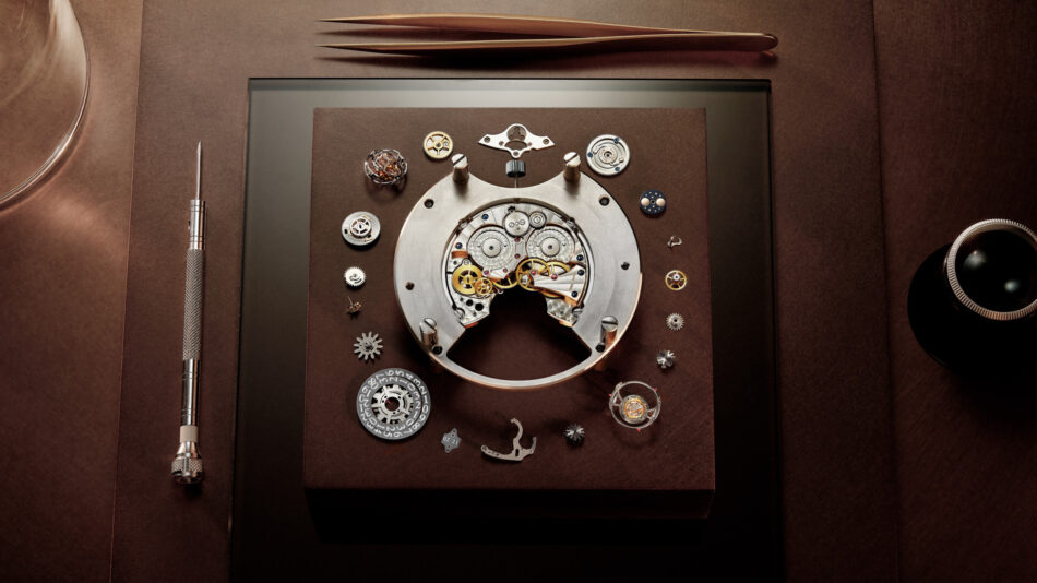 JaegerLeCoultre Duometre Heliotourbillon PerpetualCOMPONENTES Watches World Disassembled mechanical watch movement with gears and plates laid out on a brown display board surrounded by watchmaking tools