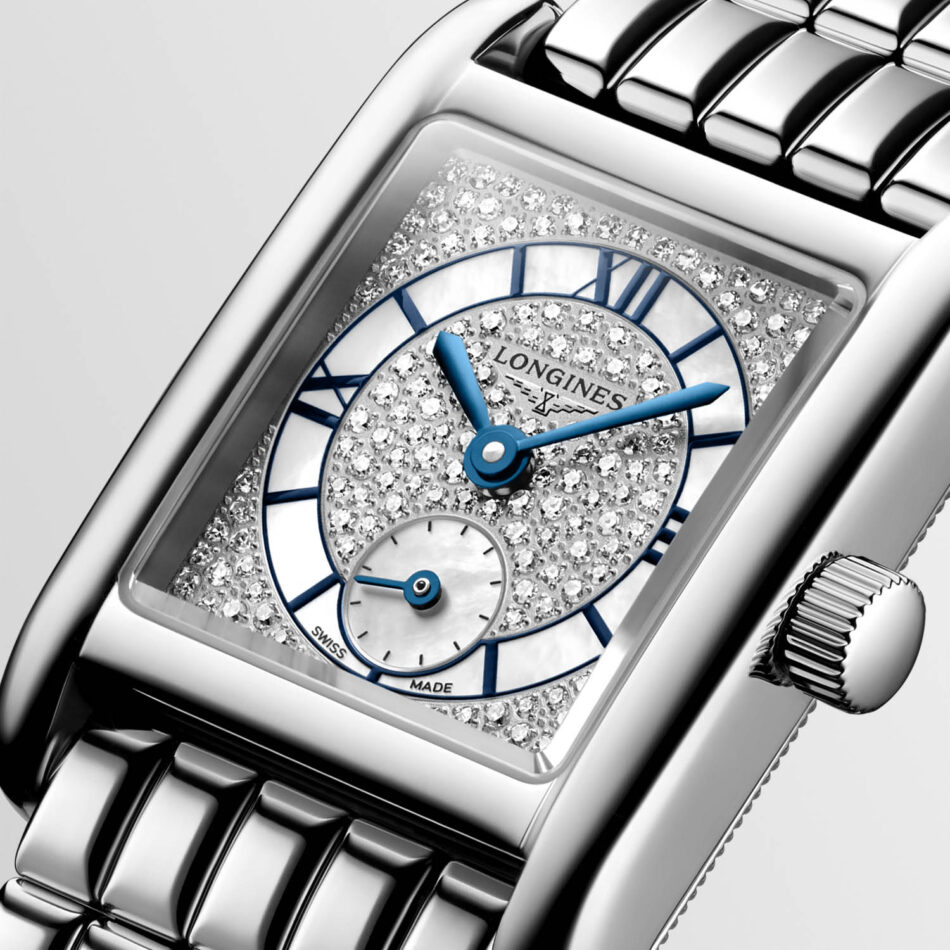 Longines presenta los Mini DolceVita más brillantes y sofisticados hasta la fecha Watches World Close up of a rectangular diamond studded Longines watch with blue hands and a jeweled dial metal bracelet visible on the sides