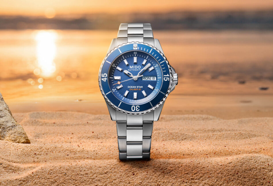MIDO Ocean Star 200 el reloj de buceo suizo que combina resistencia y 80 horas de autonomía Watches World Blue dial Mido Ocean Star automatic watch with a stainless steel bracelet on a sandy beach at sunset