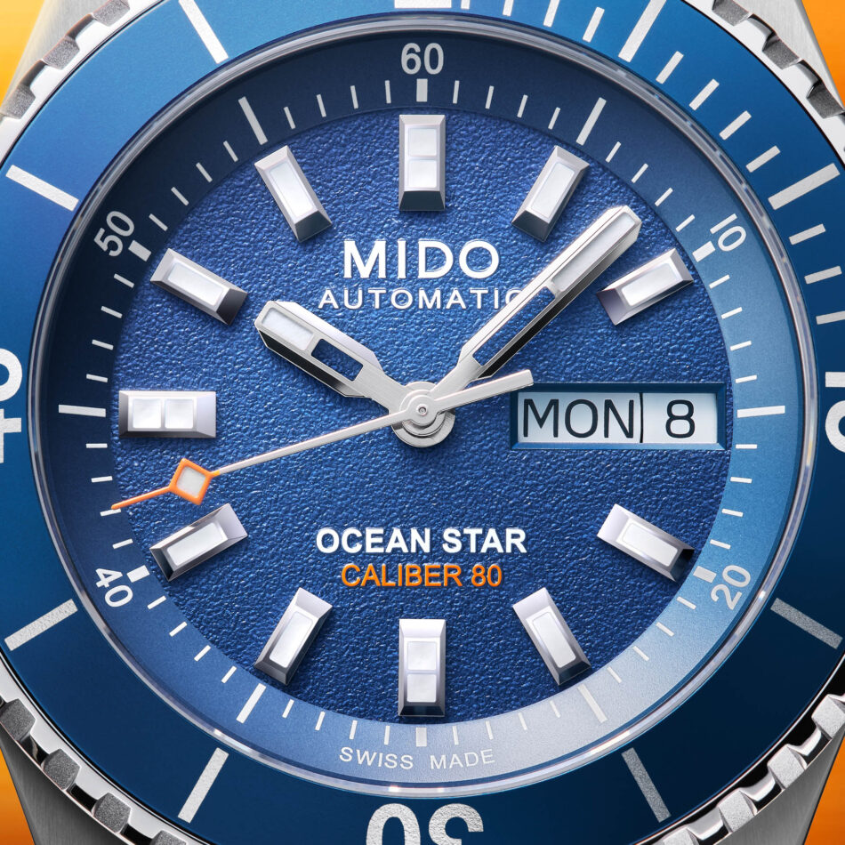 MIDO Ocean Star 200 precisión resistencia al agua y espíritu aventurero Watches World Close up of a blue MIDO Ocean Star watch dial with silver hour markers and a daydate window showing MON 8
