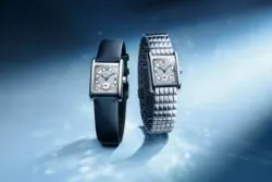 Two luxury square-dial watches with diamond-studded faces, one on a blue strap and one on a metal bracelet, on a blue icy background.