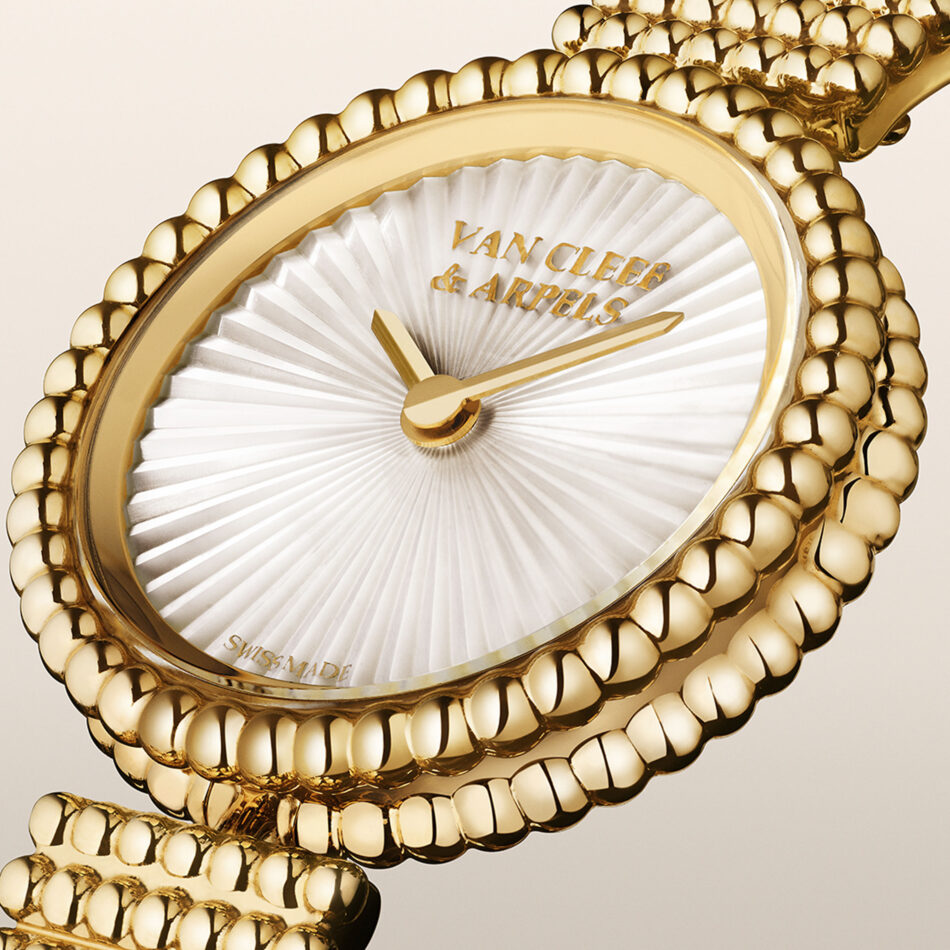 El universo relojero de Van Cleef Arpels brilla a través de la colección Perlée Watches World Primer plano de una pulsera de cuentas doradas con una cadena de eslabones texturizados en el que destacan sus esferas pulidas y su brillo metálico
