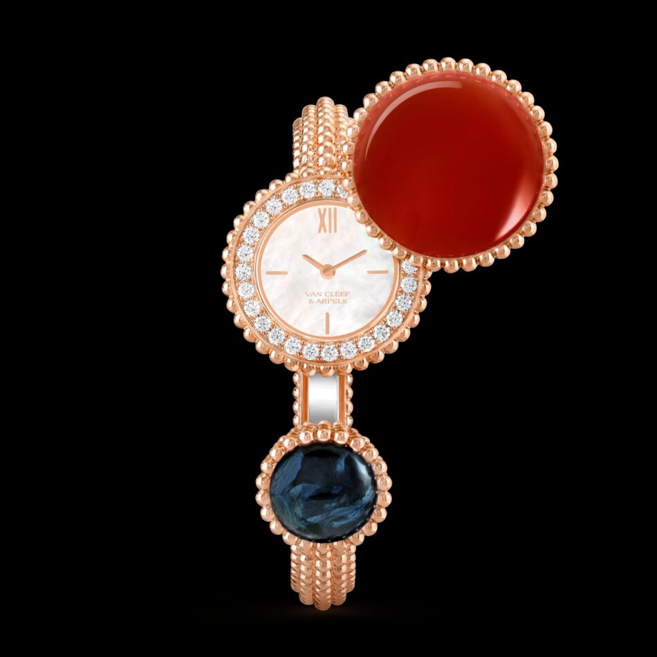 Perlée Van Cleef Arpels5png Watches World Reloj de lujo de oro rosa con bisel engastado con diamantes un cabujón ovalado rojo en la parte superior y una gema de color azul intenso en la parte inferior sobre un fondo negro