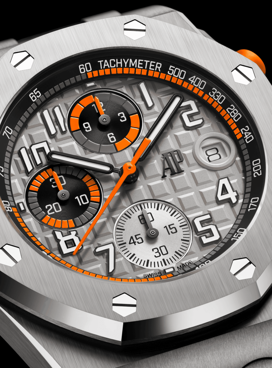 ROYAL OAK OFFSHORE dial Watches World Close up of a luxury chronograph watch face with orange accents and tachymeter scale showing subdials and AP logo prominently