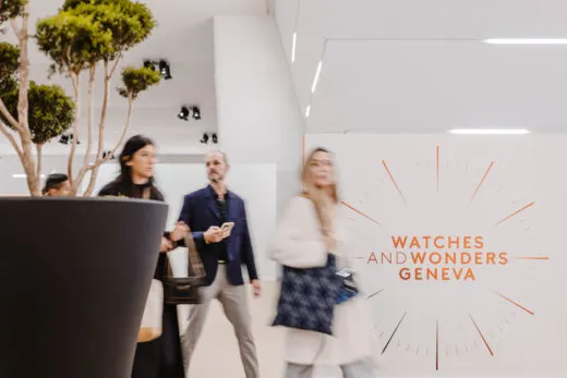 Imagen borrosa de un grupo de personas en un moderno stand de una feria, con un cartel blanco en la pared en el que se lee «WATCHES AND WONDERS GENEVA».