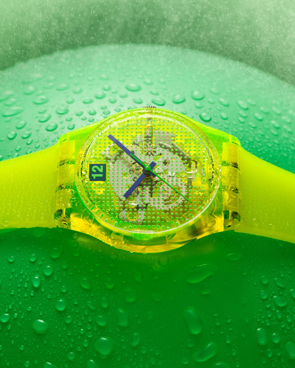 La nueva colección Swatch SMASH IT apuesta por colores intensos y diseño audaz Watches World Close up of a neon yellow wristwatch with a perforated dial on a green water dappled surface