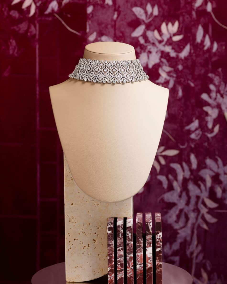 276255phAntonio Barrella4x5 Watches World Diamond choker necklace on a beige mannequin bust against a maroon patterned background