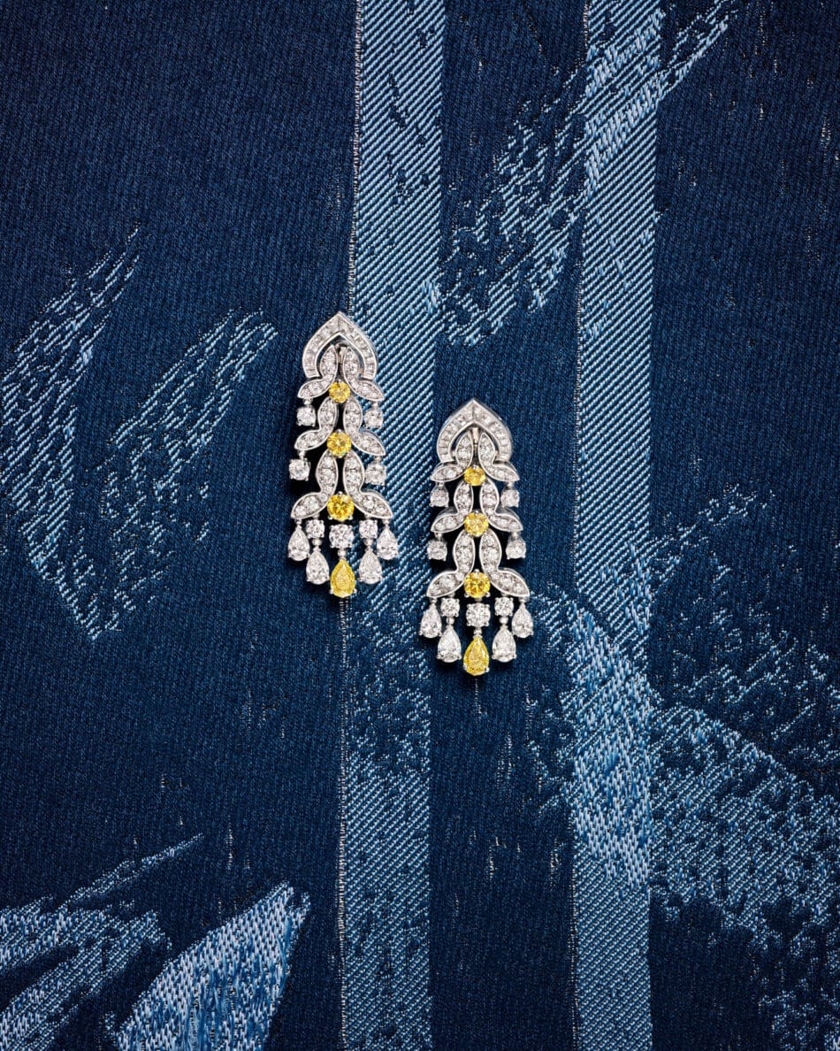 276802phAntonio Barrella4x5 Watches World Dangling diamond earrings with yellow gemstones placed on dark blue denim fabric with white stitching patterns close up detail