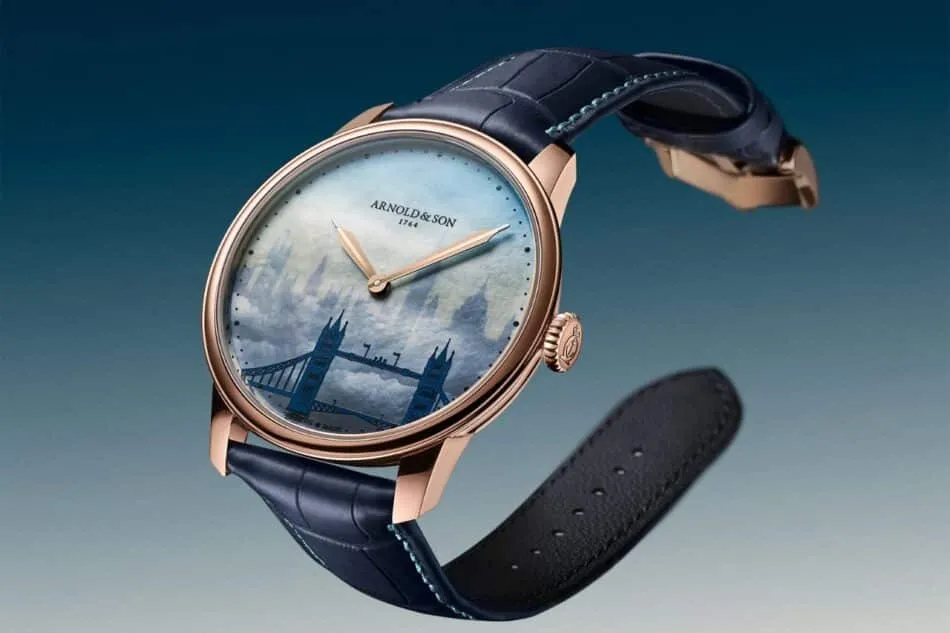 Rose gold watch with a blue leather strap and a pale blue dial featuring a London Tower Bridge scene.