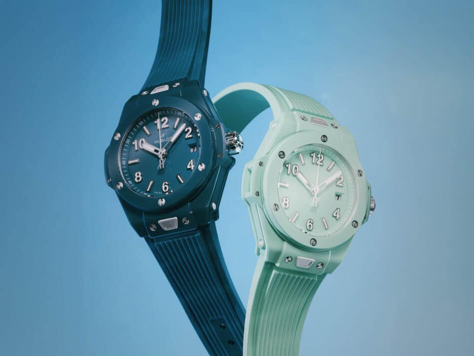 BIG BANG PETROL BLUE AND MINT GREEN CERAMIC 1 Watches World Two sport watches in blue and mint green overlap diagonally against a blue background showcasing their faces