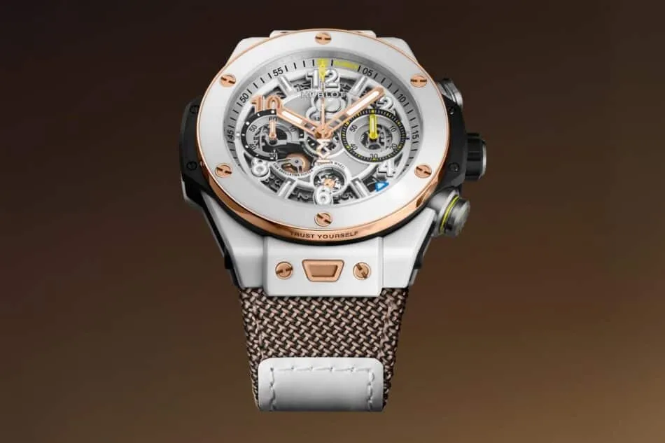 Skeleton chronograph watch with white case, rose-gold accents, and a woven metal strap showcasing exposed gears and dials.