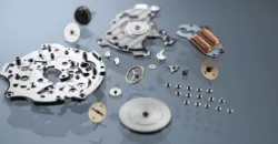 Calibre Spring Drive 9RB2 Exploded view of a mechanical watch movement with gears, plates, and springs laid out on a reflective surface