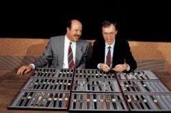 Oris Star y Dr Portmann Two men in suits examine a large display case filled with many wristwatches on a table outside against a dark background