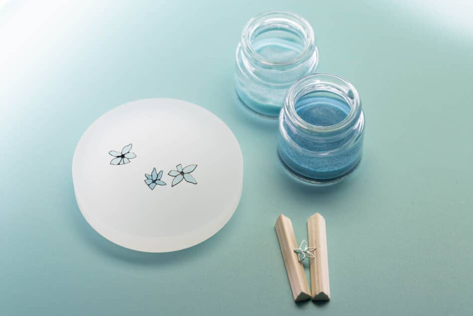 Tiffany Craft The enamel flowers 2 Tiffany Co Watches World Conjunto para nail art con una bandeja blanca decorada con flores azules dos pequeños frascos de gel azul y pinzas de madera sobre una superficie de color menta