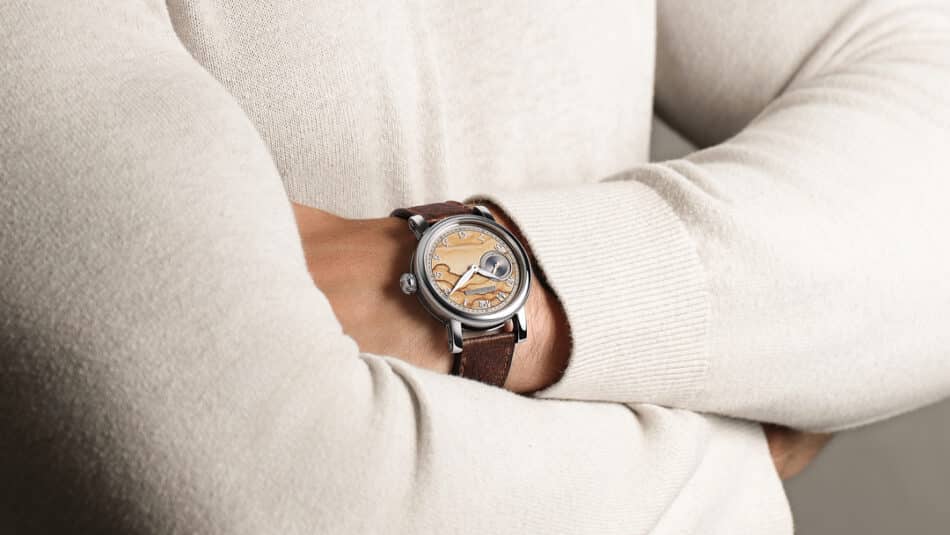 Chronoswiss Small Second Jasper Style Watches World Person's arm crossed wearing a vintage wristwatch with a tan dial and brown leather strap against a cream sweater edge.