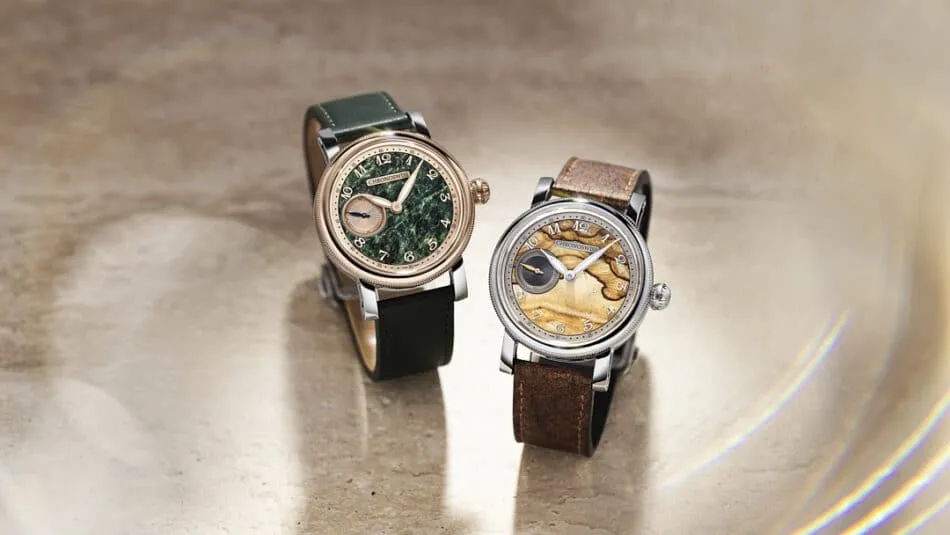 Two luxury wristwatches with leather straps sit on a beige stone surface; green dial with rose-gold case on the left, tan dial with silver case on the right.